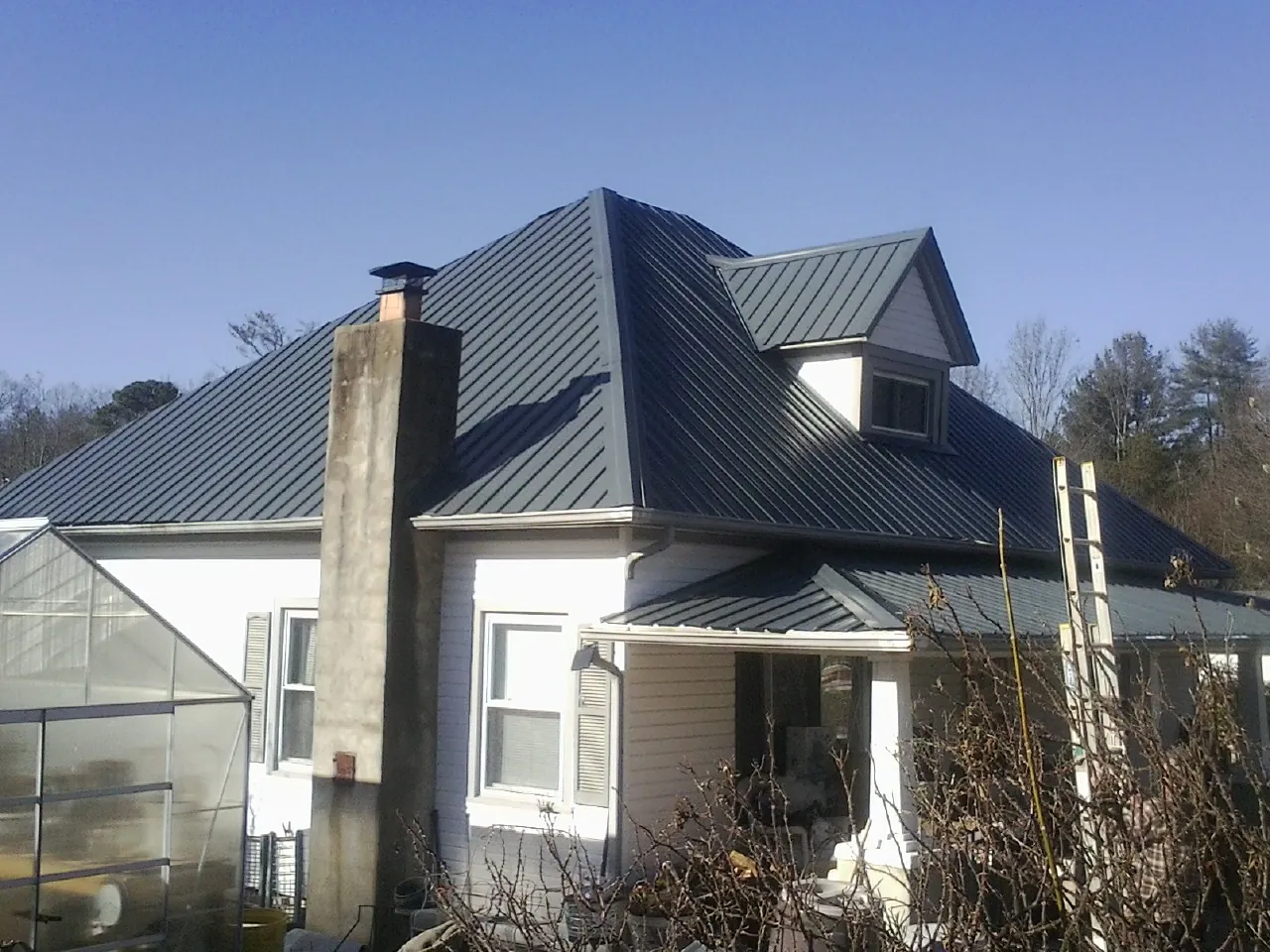 Dark blue standing seam metal roof on a white farmhouse with dormer — Slate & Tile Roof Repair by Roofing Brothers in Landisville