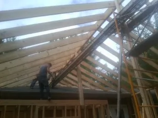 Rafters going up over a new addition with a worker on the wall in Landisville