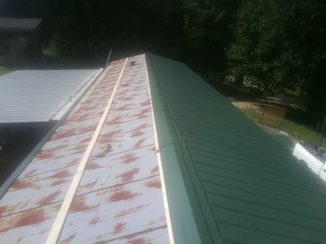 Old rusted panels beside newly installed green metal roofing — Wind Damage Roof Repair by Roofing Brothers in Landisville