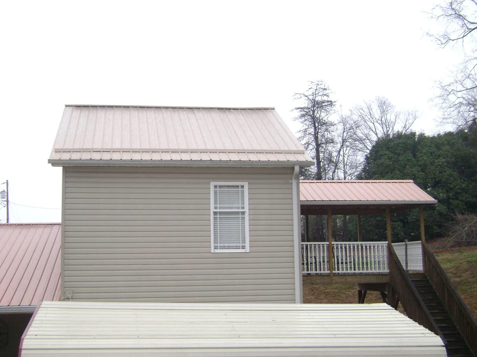 Tan metal roofs on a two story addition and attached porch, from a Roof Replacement job in Landisville